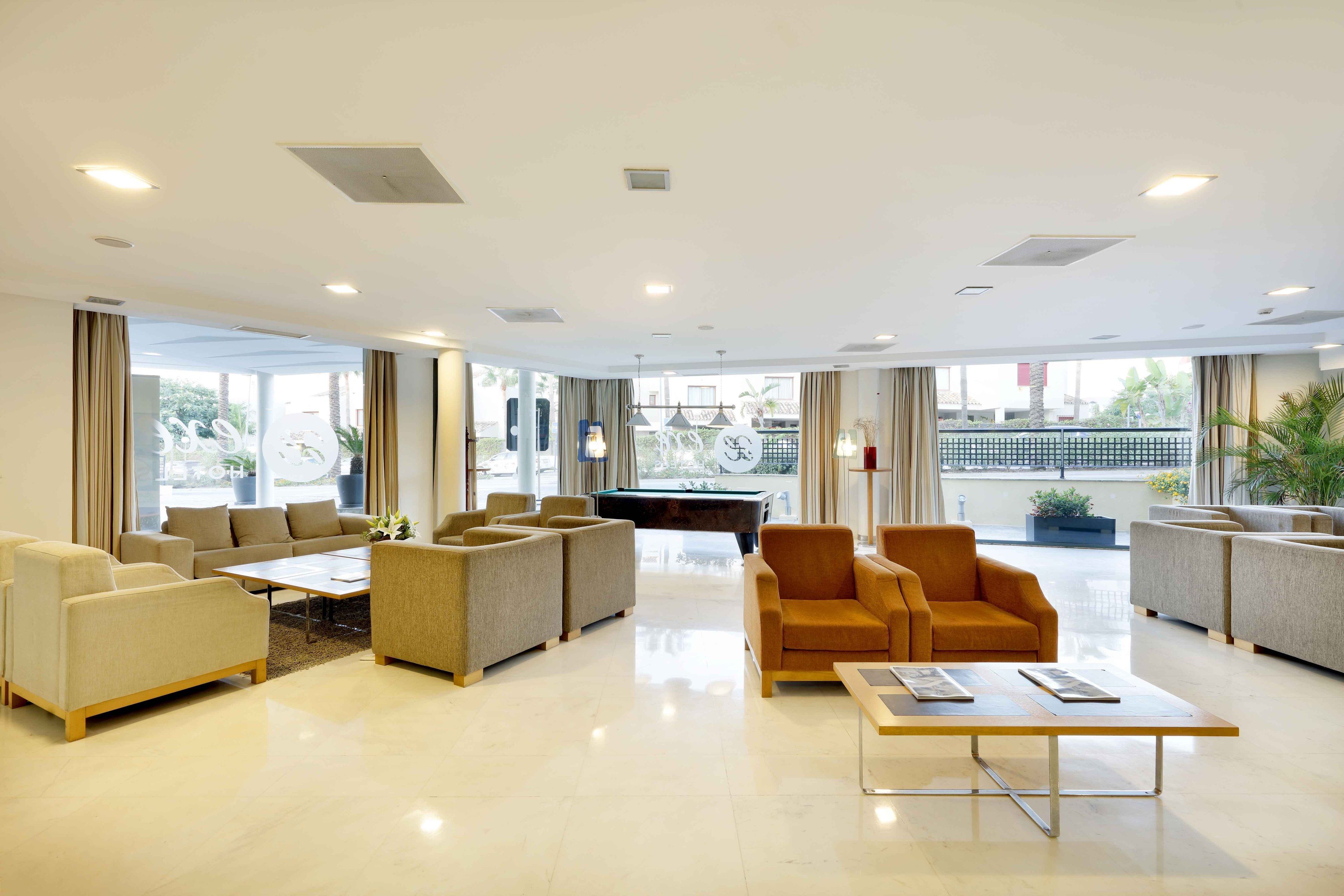 Un vestíbulo espacioso con mesa de billar, asientos cómodos y grandes ventanales con vistas al exterior.