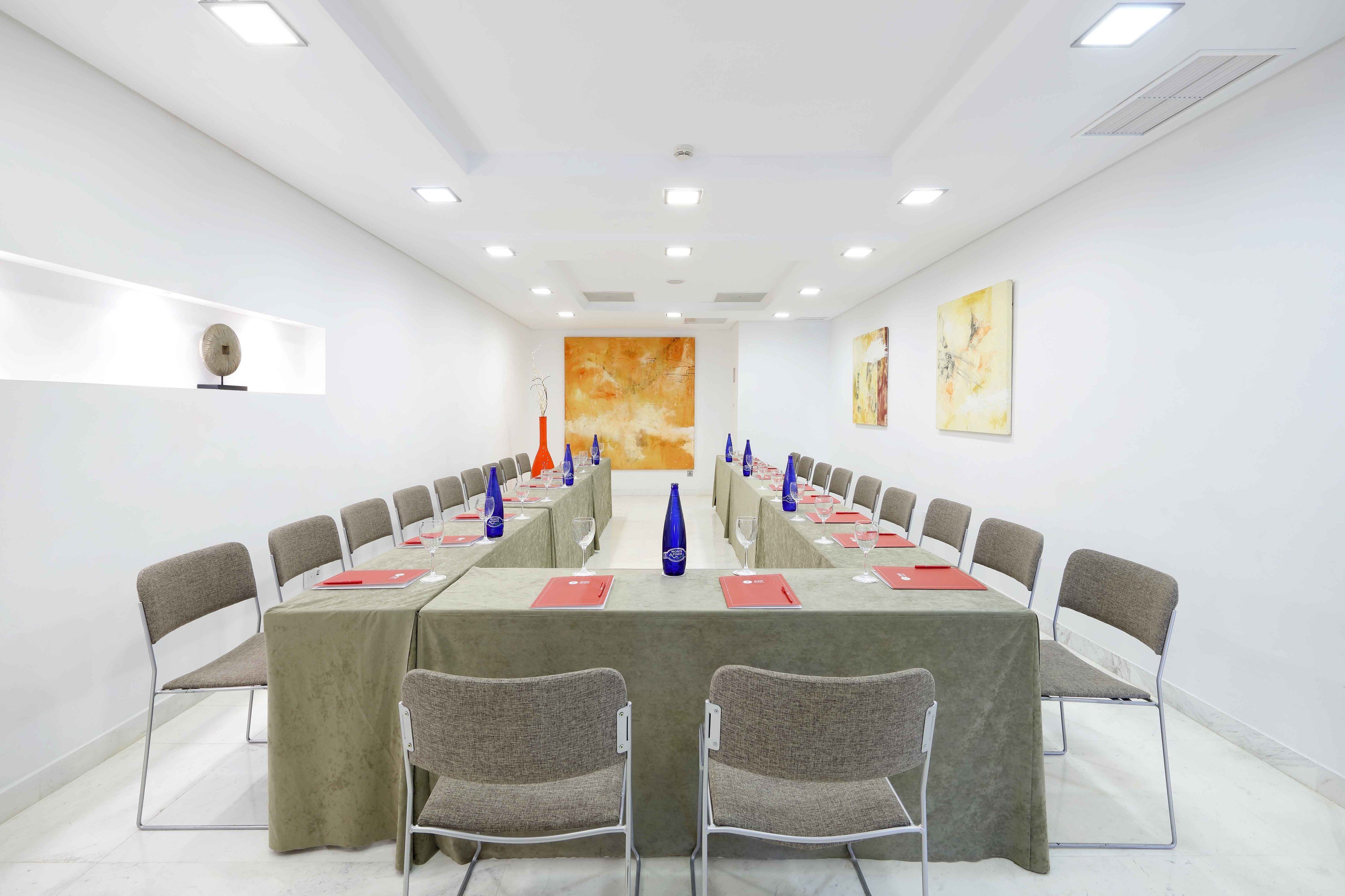 Ein Konferenzraum mit einem langen Tisch, Stühlen und blauen Vasen.