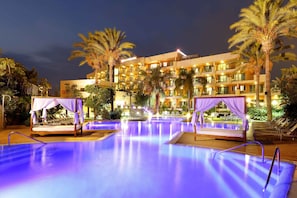A hotel pool area with two sunbeds and a canopy, surrounded by palm trees and a building with multiple balconies. - Exe Estepona Thalasso & Spa - Adults only Recommended (Estepona)