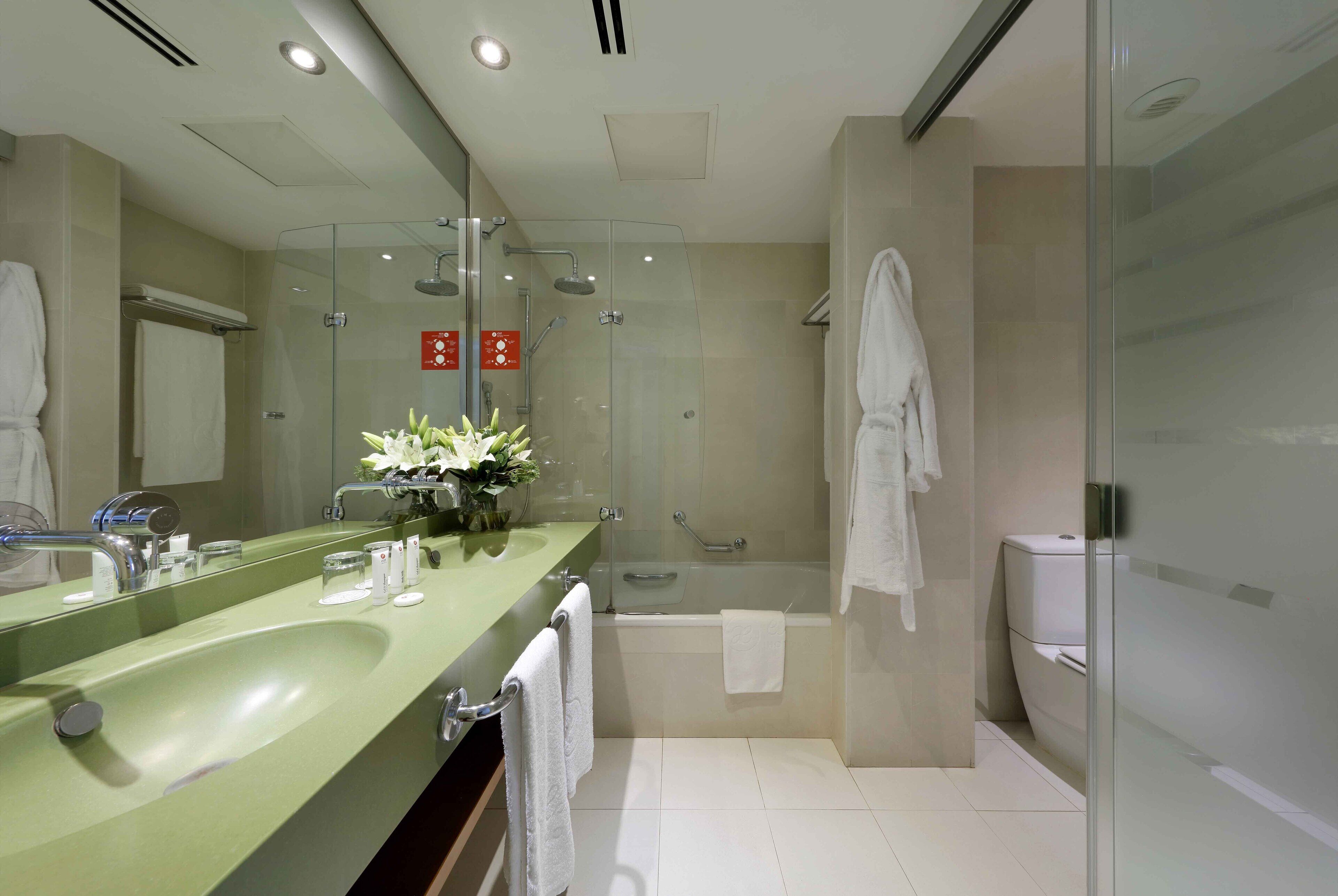 A modern bathroom with a green sink, a glass-enclosed shower, and a white toilet.