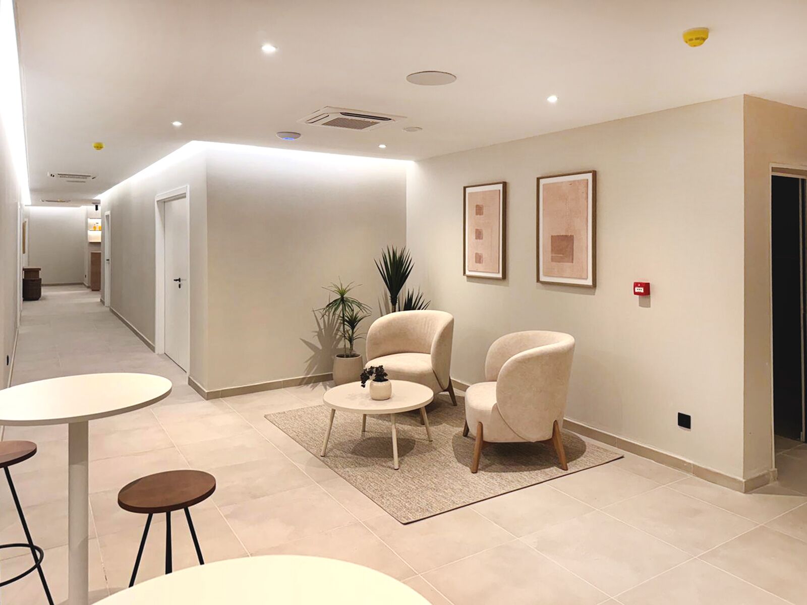 A modern hotel lobby with a reception desk, seating area, and framed artwork on the walls.