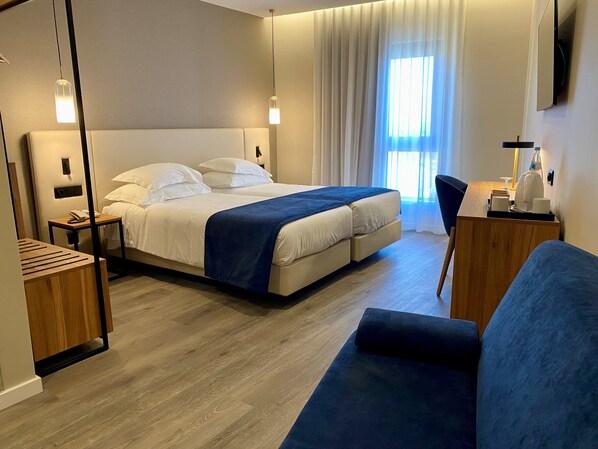 A modern hotel room with a large bed, bedside tables, a desk, and a chair.