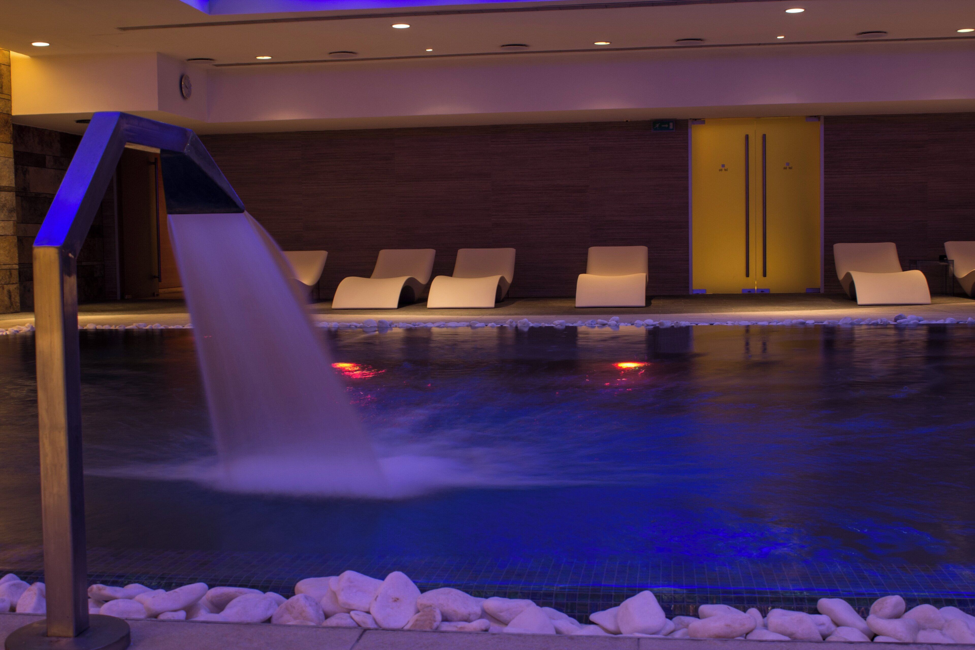 Un área de piscina con sillones de descanso y una fuente.