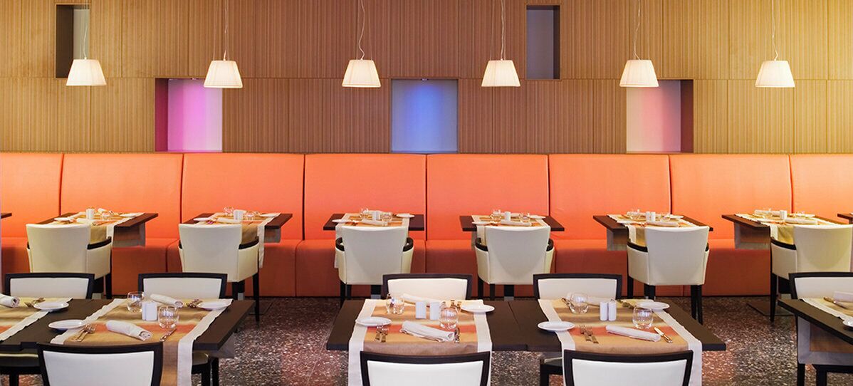Una sala ristorante con banconi e tavoli, ognuno apparecchiato con posate e bicchieri.