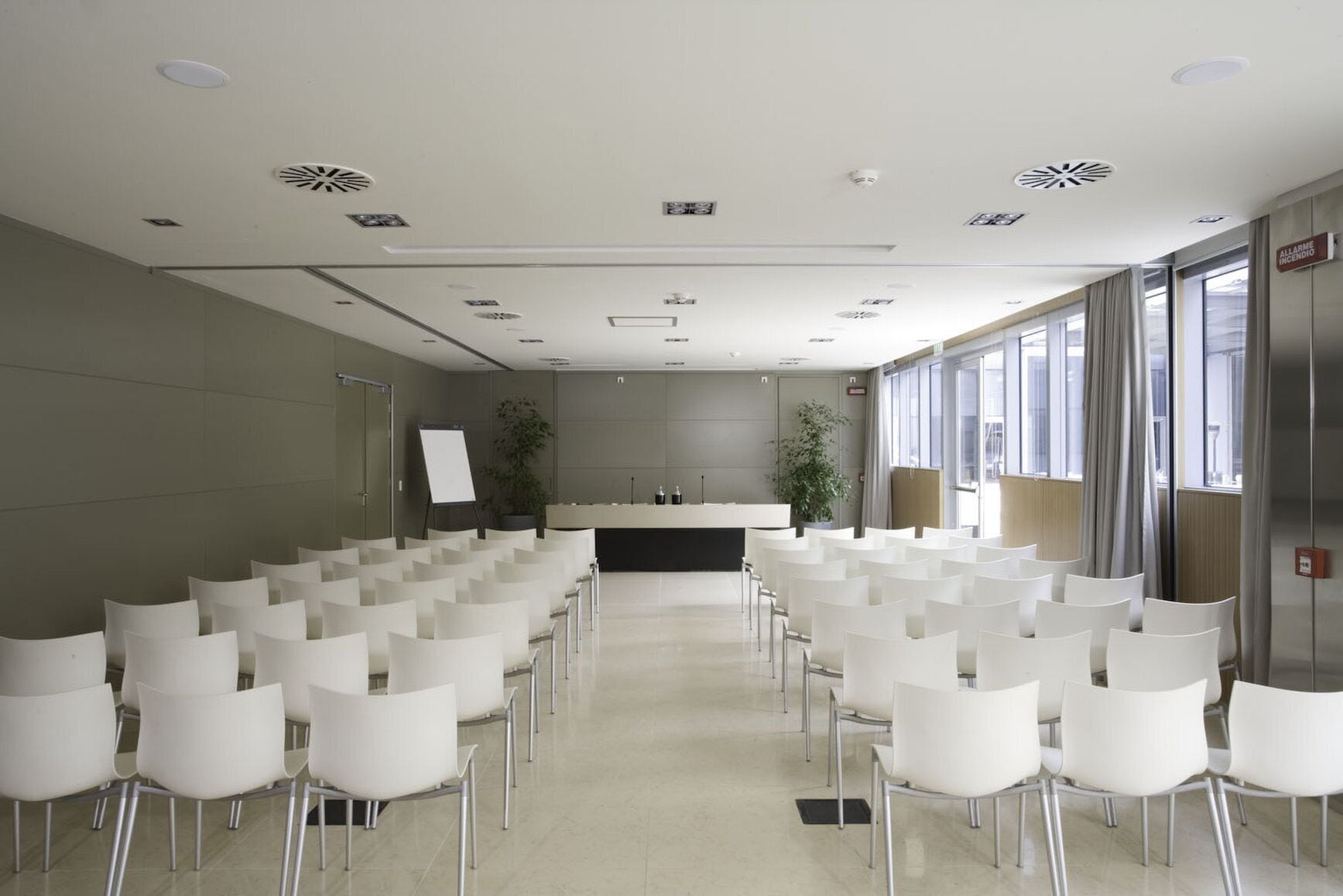 A conference room with rows of white chairs, a podium, and a whiteboard.