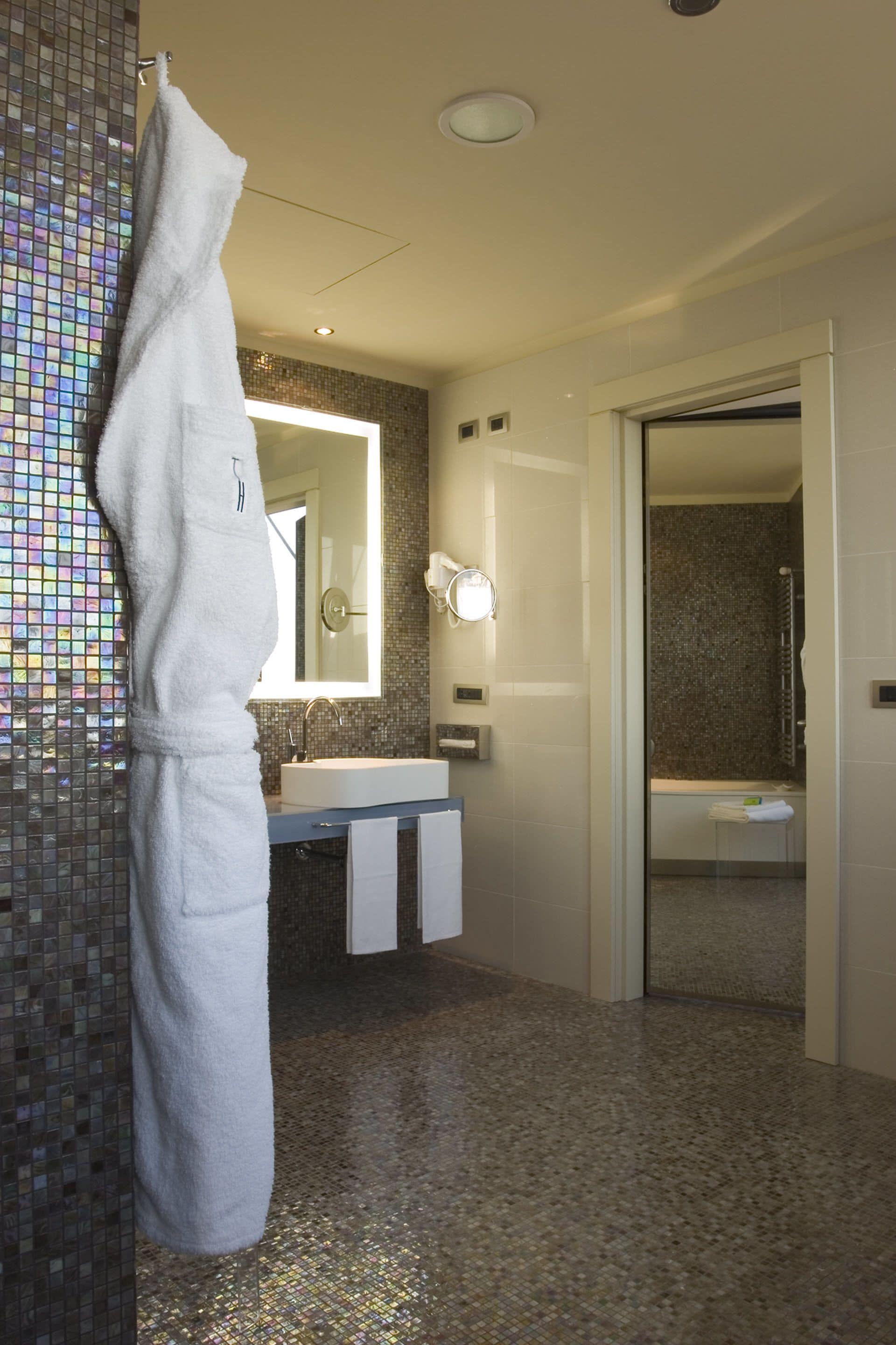 A modern bathroom with a large mirror, a sink, and a glass shower enclosure.