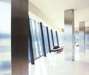 Un pasillo moderno con ventanas amplias, un banco y una zona de recepción.