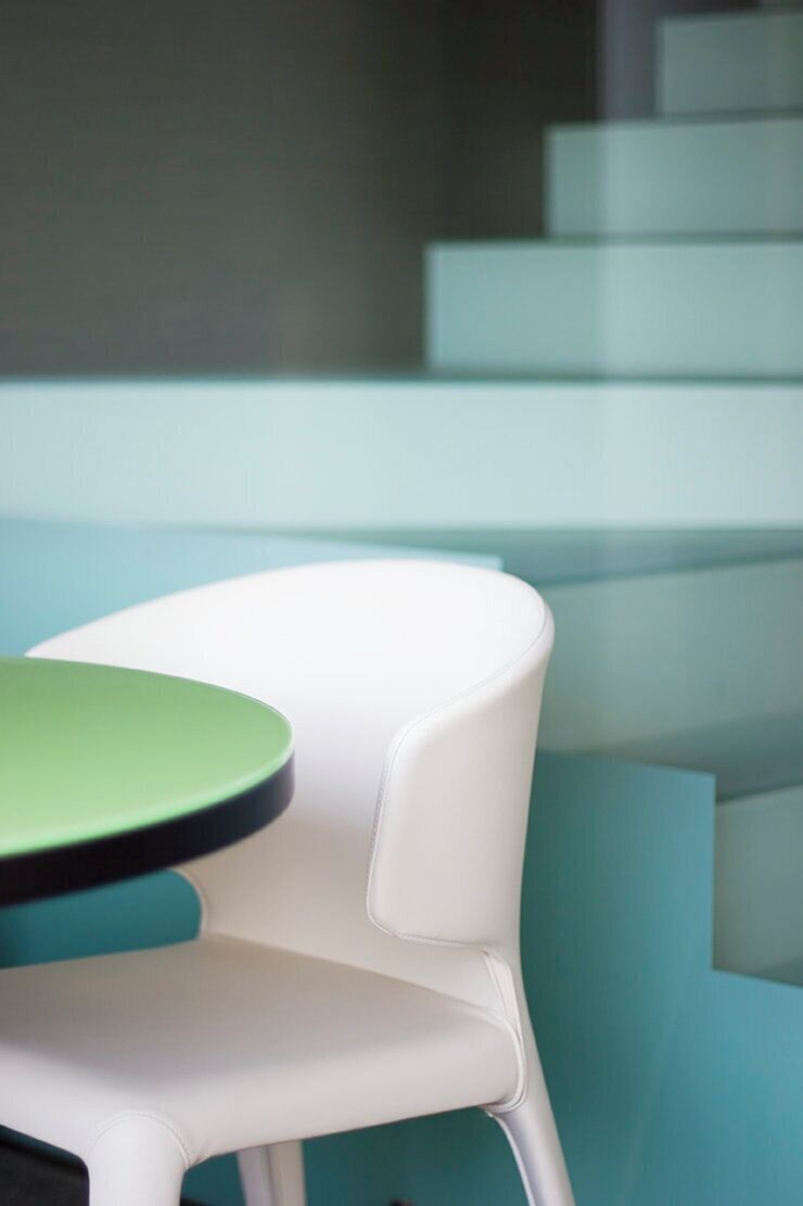 A modern interior with a white chair and a green table.
