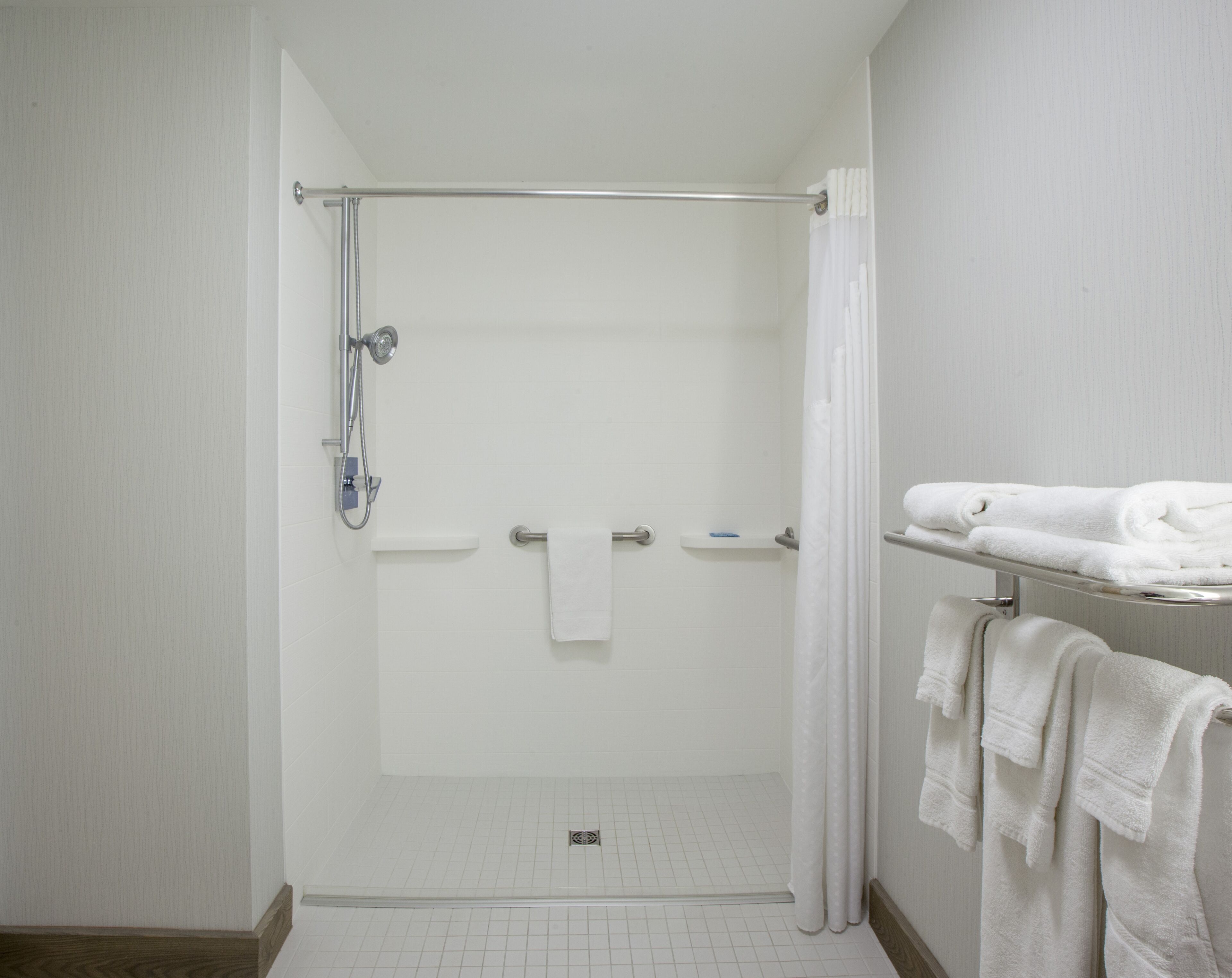 A modern bathroom with a glass-enclosed shower, a white towel rack, and a tiled floor.