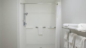 Un baño moderno con ducha de vidrio, toallero blanco y piso de baldosas.