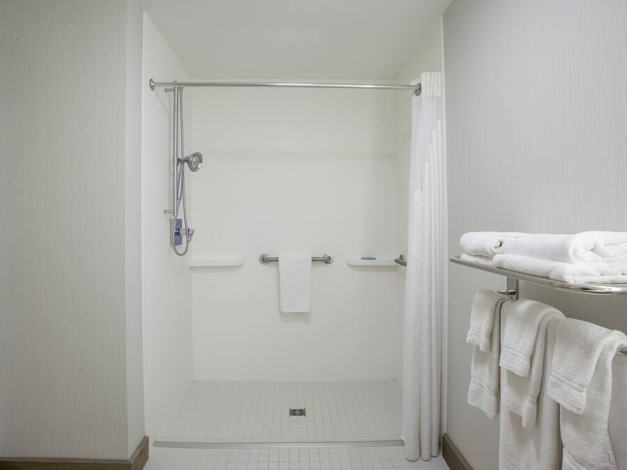 Un baño moderno con ducha de vidrio, toallero blanco y piso de baldosas.