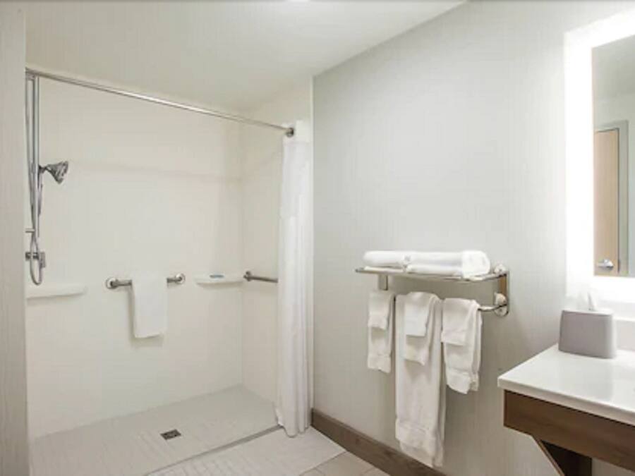 A bathroom with a shower, a sink, and a mirror.