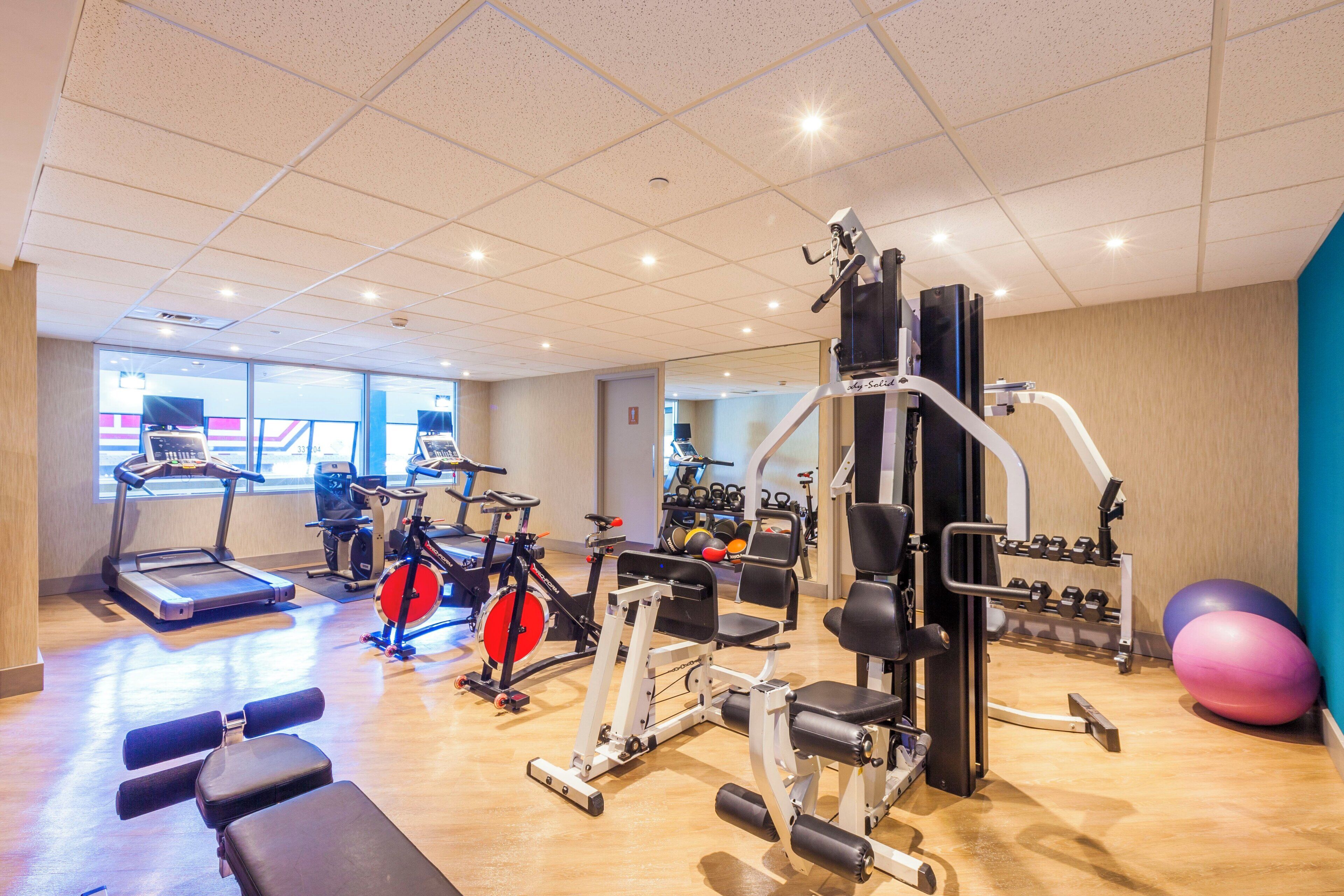 Un gimnasio con diversos equipos de ejercicio, incluyendo cintas de correr, bicicletas estáticas y máquinas de pesas.