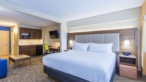 A hotel room with a large bed, a desk with a chair, a kitchenette, and a flat-screen TV. - Holiday Inn Express Saint John Harbour Side by IHG (Saint John)