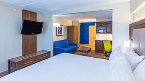 A hotel room with a bed, a blue sofa, a small table, a TV mounted on the wall, and a kitchenette in the background. - Holiday Inn Express Saint John Harbour Side by IHG (Saint John)