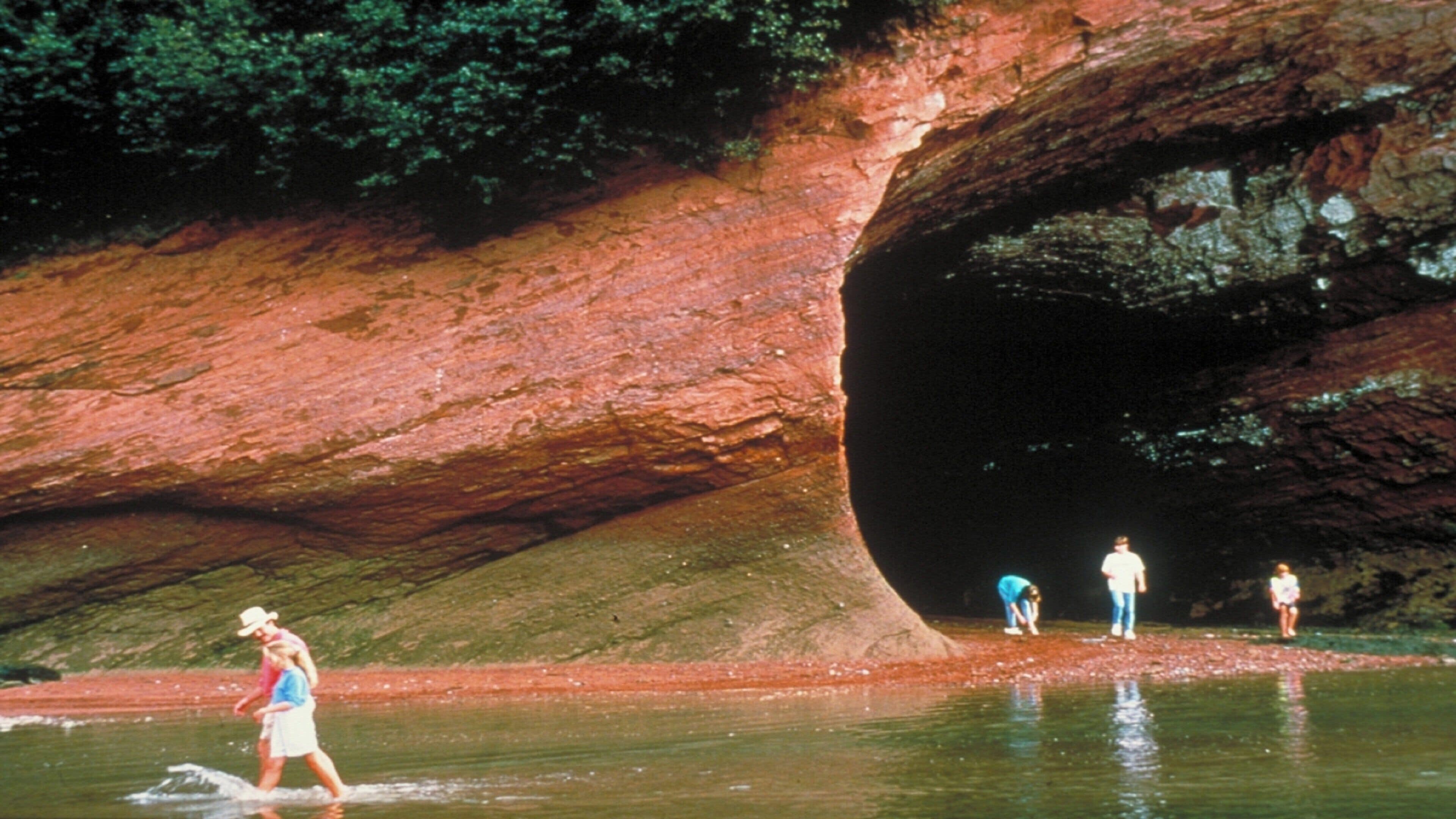 A natural rock formation with a water body in front.