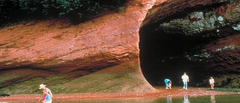 A natural rock formation with a water body in front.