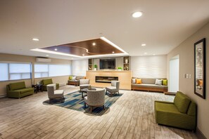 A modern living room with a fireplace, seating area, and a flat-screen TV. - Holiday Inn Express Saint John Harbour Side by IHG (Saint John)