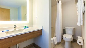 A bathroom with a sink, mirror, toilet, shower curtain, and towel rack. - Holiday Inn Express Saint John Harbour Side by IHG (Saint John)