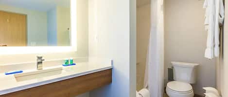Un baño con lavamanos, espejo, inodoro, cortina de ducha y toallero.