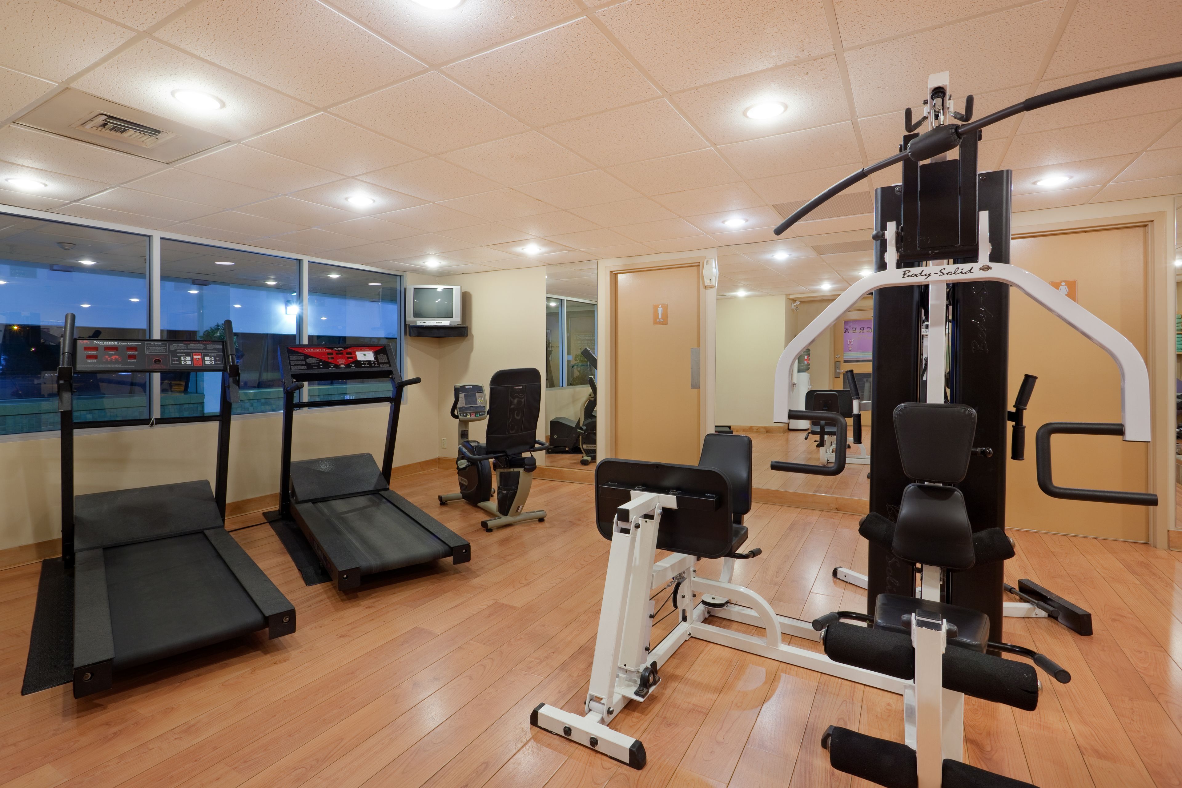 Une salle de sport équipée de tapis de course, d’appareils de musculation et d’autres équipements d’exercice.