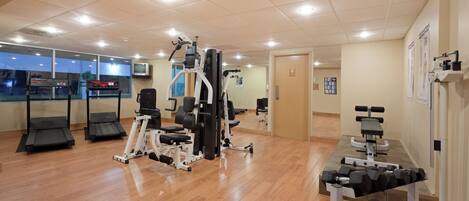 A gym with various exercise equipment, including treadmills, weight machines, and dumbbells.