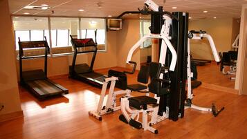 Ein Fitnessstudio mit Laufbändern, Kraftgeräten und einer Spiegelwand.