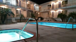 A hotel with a swimming pool, multiple balconies, and lounge chairs. -  Pacific Inn (Oceanside)