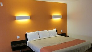 A hotel room with a bed, two bedside tables, and two wall-mounted lights. -  Pacific Inn (Oceanside)
