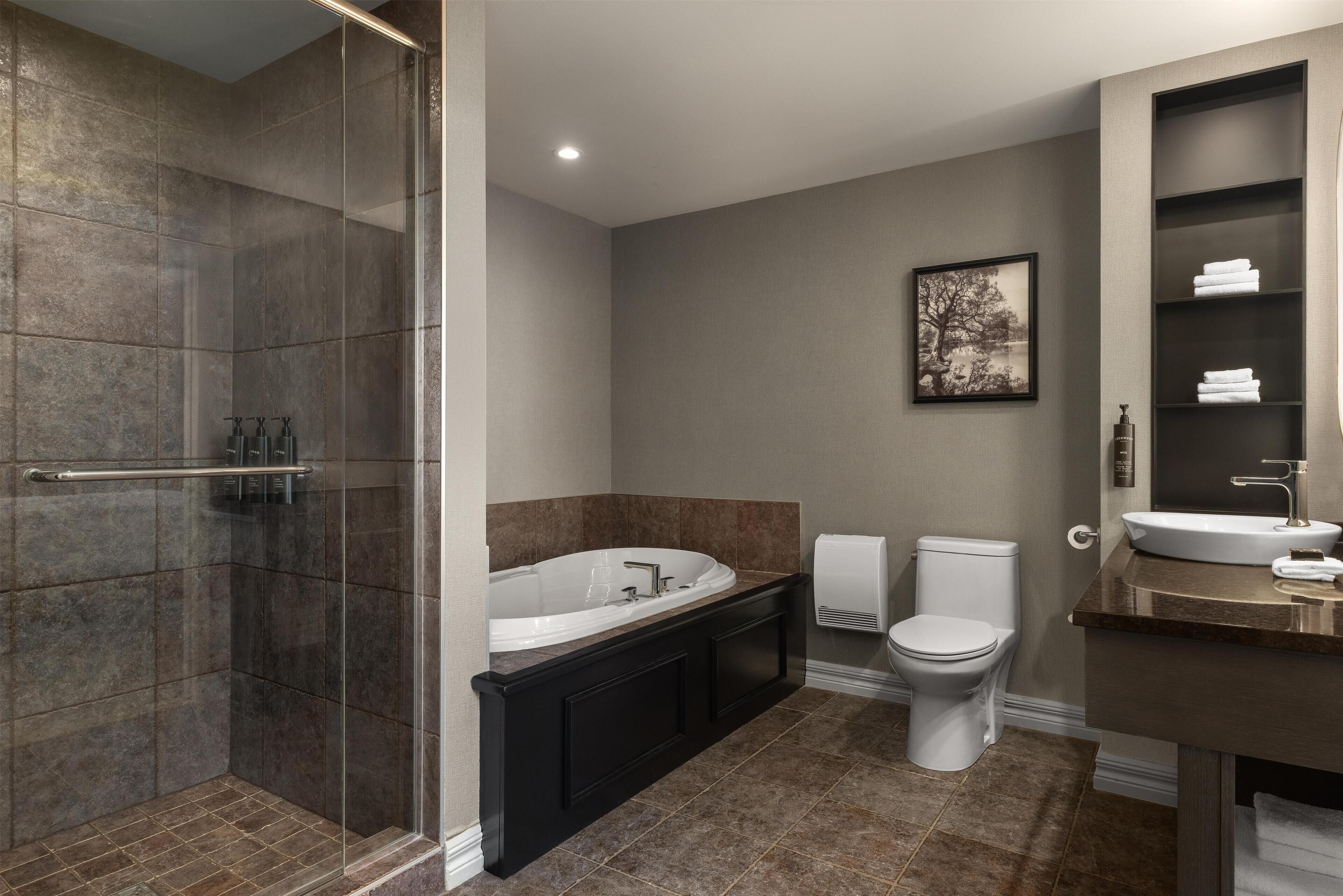 Une salle de bain moderne dotée d’une douche à l’italienne, d’une baignoire sur pieds, de toilettes et d’un lavabo.