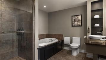 Une salle de bain moderne dotée d’une douche à l’italienne, d’une baignoire sur pieds, de toilettes et d’un lavabo.