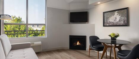 Una sala de estar moderna con chimenea, un sofá, una mesa de comedor con sillas y un televisor montado en la pared.