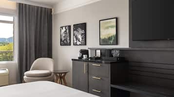 A hotel room with a bed, a chair, a small table, a cabinet, and a TV.