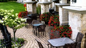 An outdoor patio area with stone walls, outdoor seating, and decorative lighting. - Hotel Vallea Bromont, Tapestry Collection by Hilton (Bromont)