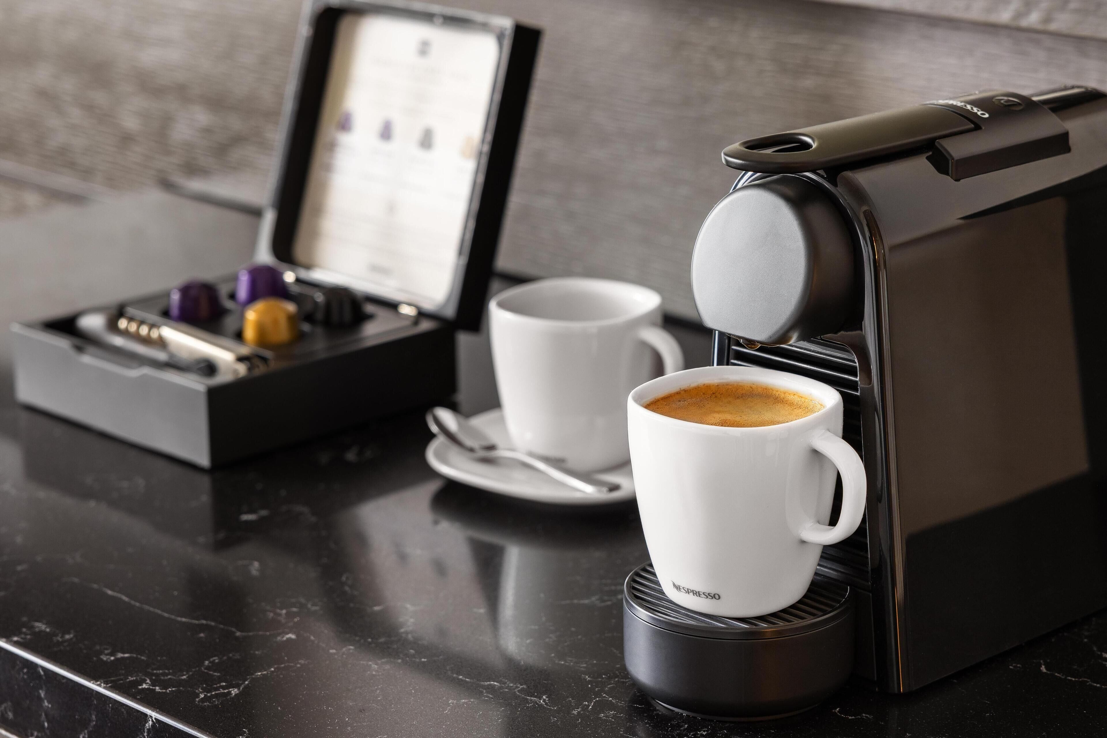 A coffee machine on a marble countertop with a cup of coffee and a box of coffee pods.