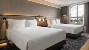 A hotel room with two beds, a large window with curtains, and a wall-mounted light fixture. - Hotel Vallea Bromont, Tapestry Collection by Hilton (Bromont)