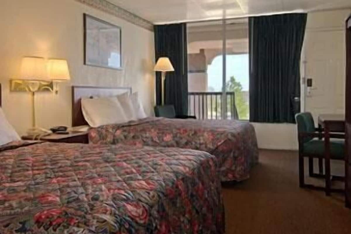 Ett hotellrum med två sängar, en balkong, ett skrivbord och en stol.
