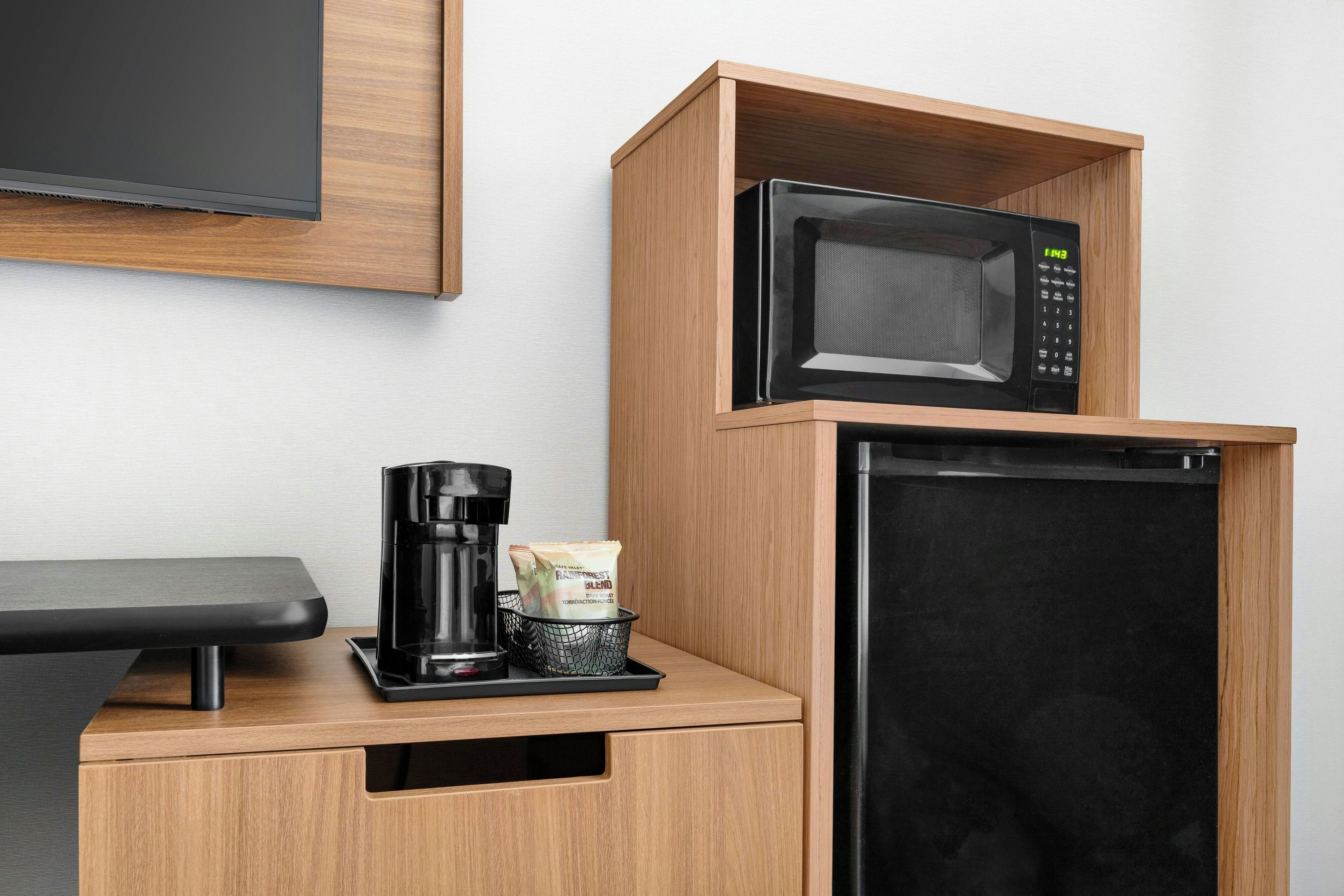 A kitchenette with a microwave, coffee maker, and storage for coffee pods.