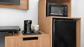 A kitchenette with a microwave, coffee maker, and storage for coffee pods.