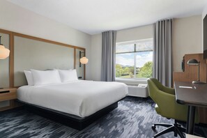 Een hotelkamer met een bed, een bureau, een stoel, een raam met uitzicht en een plafondlamp.