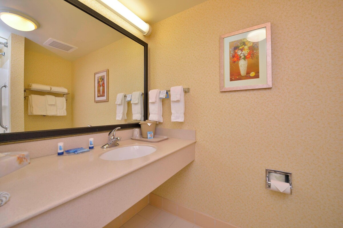Een badkamer met een wastafel, spiegel en handdoekrek.