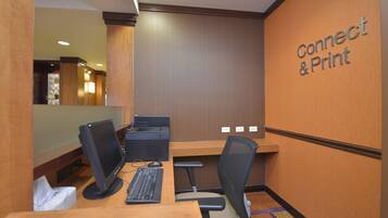 A hotel room with a desk, computer, and a sign that reads "Connect & Print".