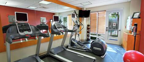 A gym with treadmills, elliptical machines, and a red exercise ball.