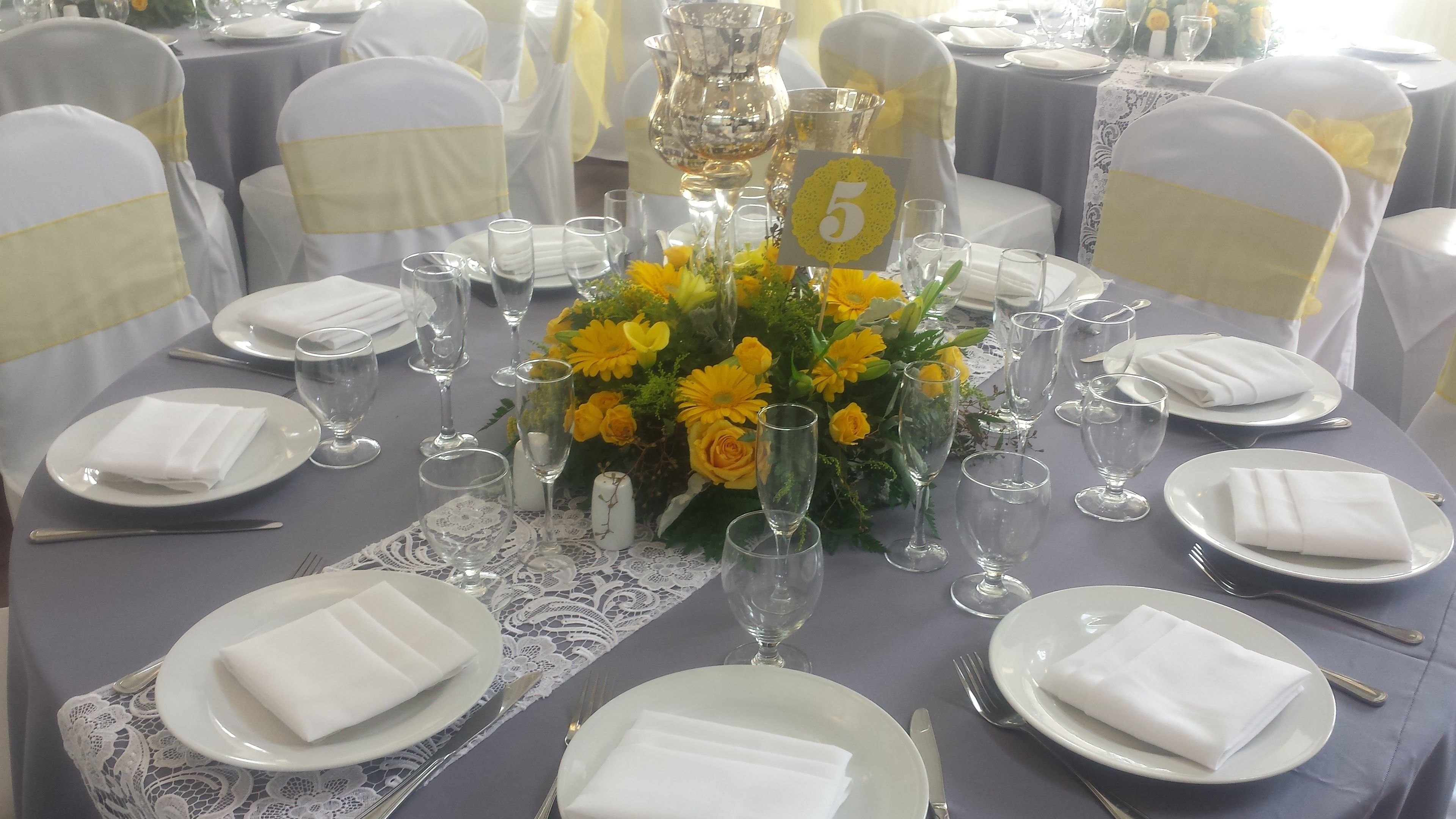 A round table set for a formal event with white tablecloths, neatly folded napkins, and clear glassware.