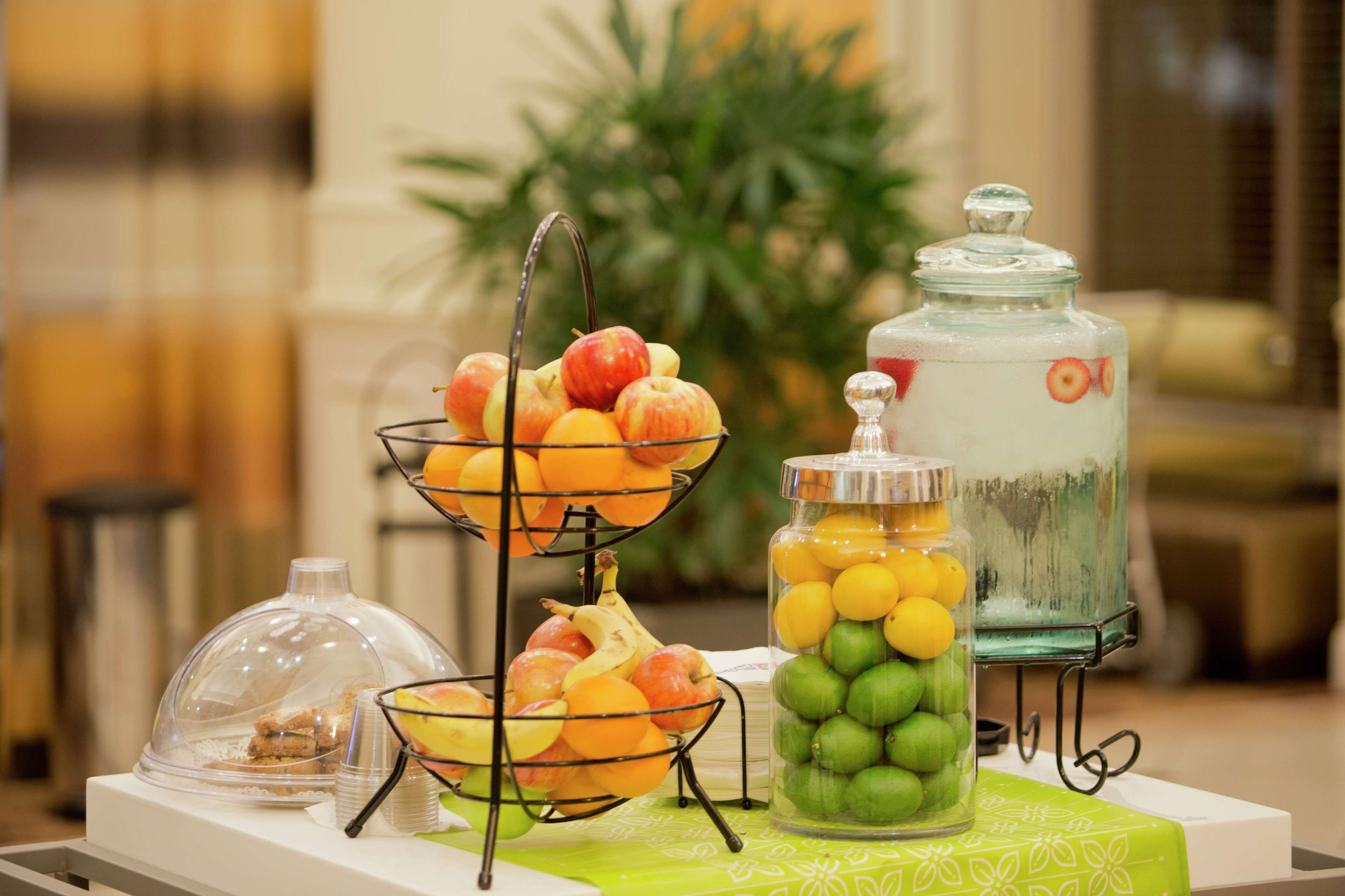Een buffetopstelling met een fruitschaal, een glazen pot met citroenen en een waterdispenser.