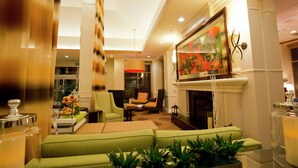 A modern living room with green sofas, a fireplace, and a large painting. - Hilton Garden Inn Oxnard/Camarillo (Oxnard)