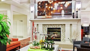 A lobby with a fireplace, seating area, and a table with a green tablecloth.