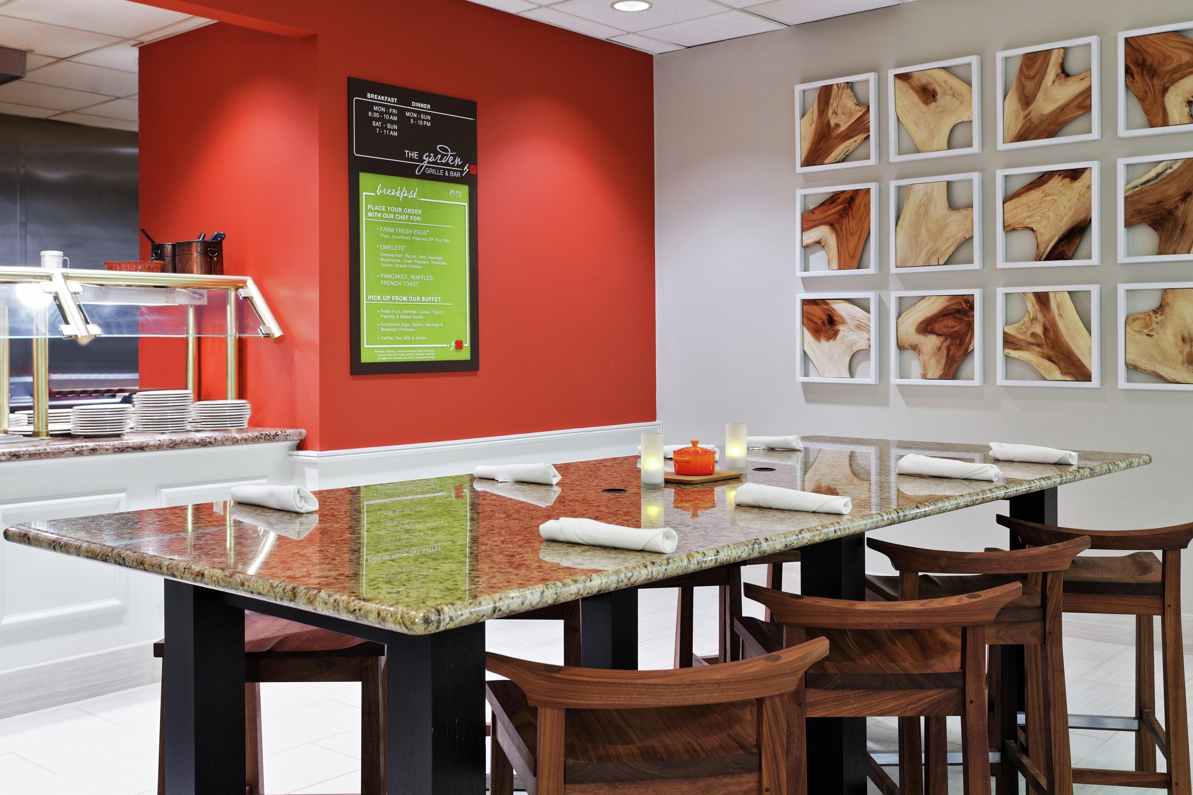 A modern dining area with a large table, wooden chairs, and a menu board on the wall.