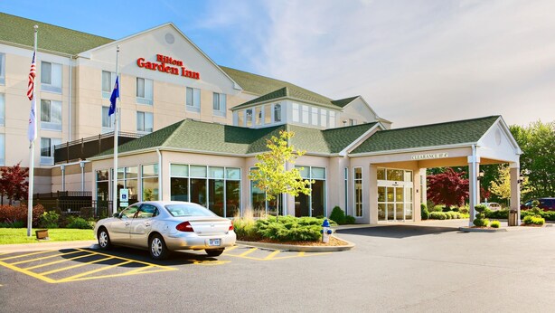 A Hilton Garden Inn with a clear entrance, a parking area, and a flag display.