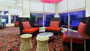 A modern lounge area with wicker furniture, red cushions, and a patterned carpet.